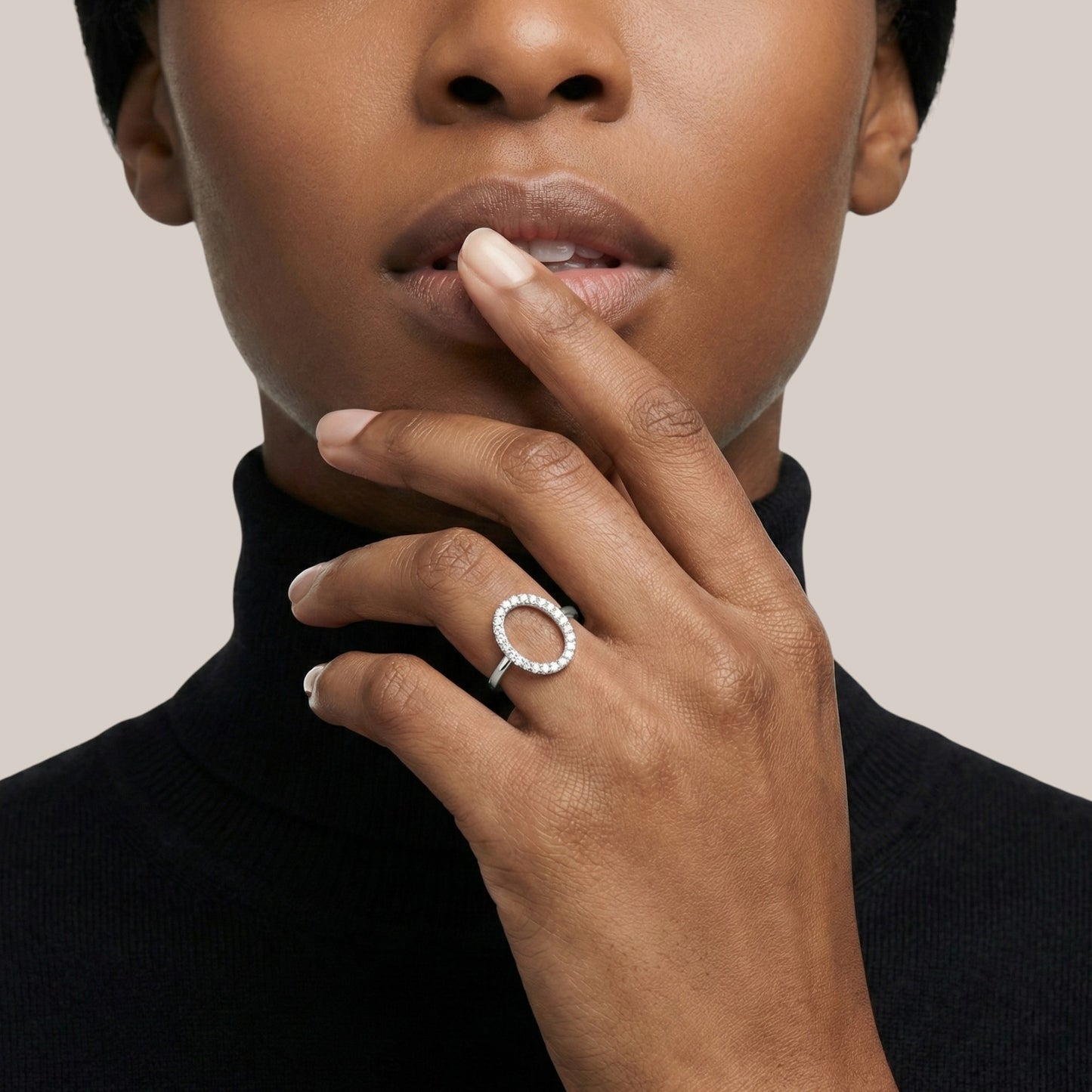 Close-up of a person wearing a silver ring on their finger, with a neutral background