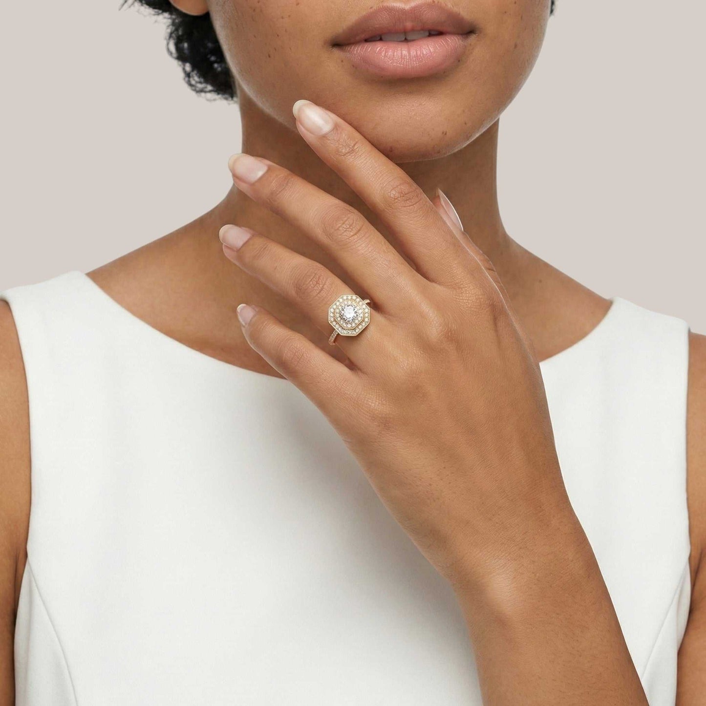 Close-up of a woman's hand wearing a diamond ring on a plain background
