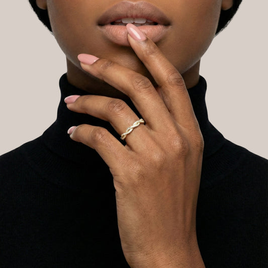 Close-up of a hand with a gold ring on a neutral background