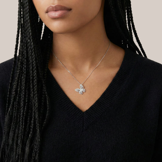 Butterfly necklace worn by a person with braided hair against a neutral background