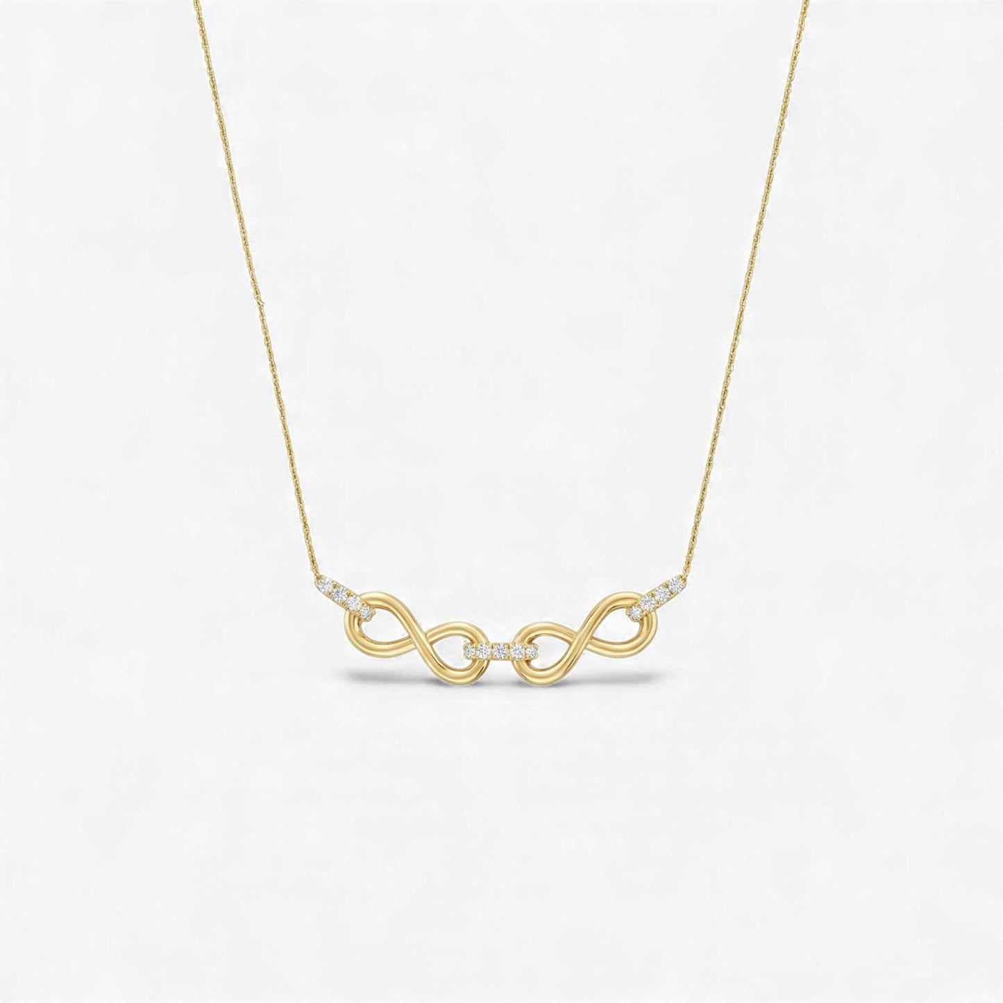 Gold necklace with a double infinity symbol pendant on a light gray background