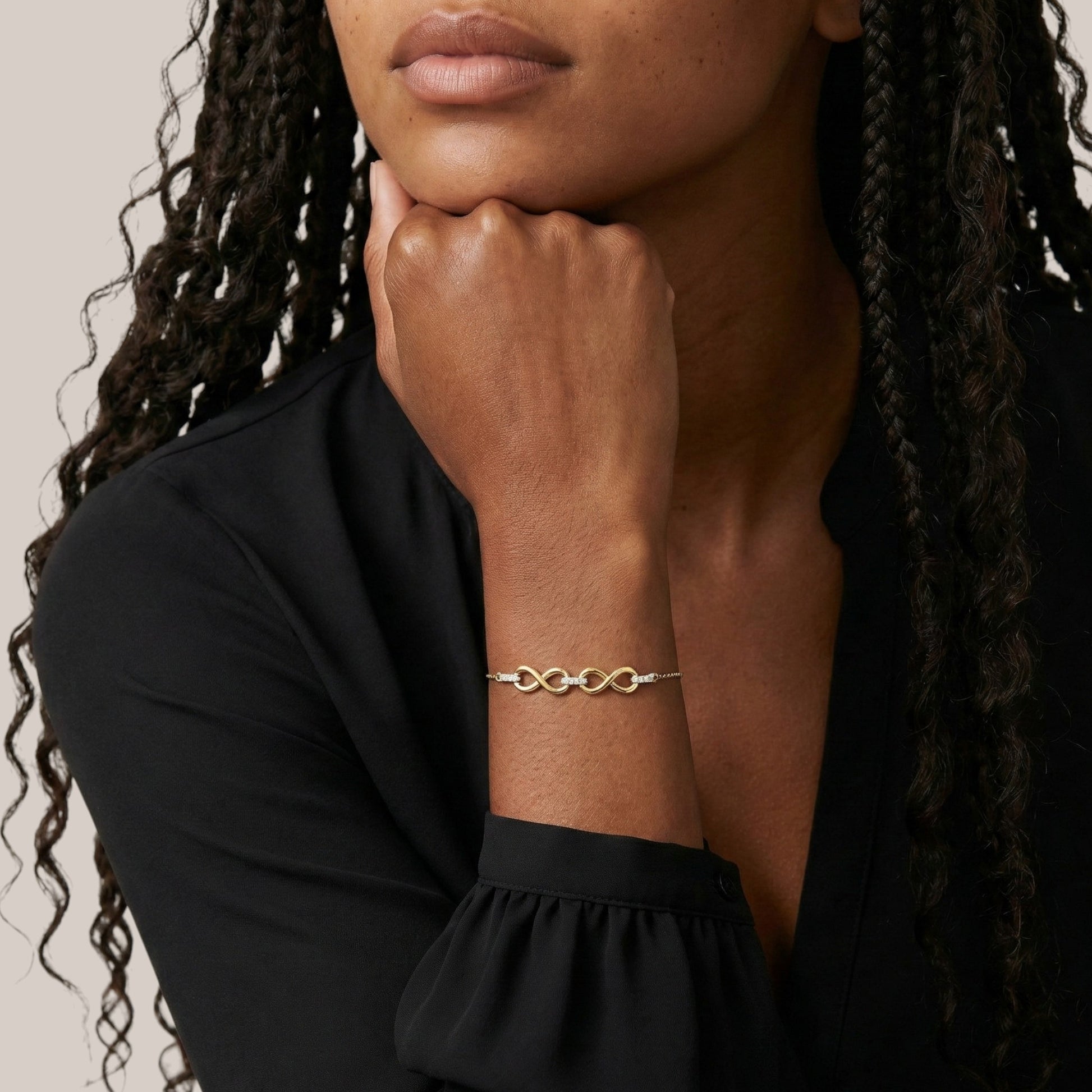Woman wearing a gold bracelet with an infinity symbol on her wrist.