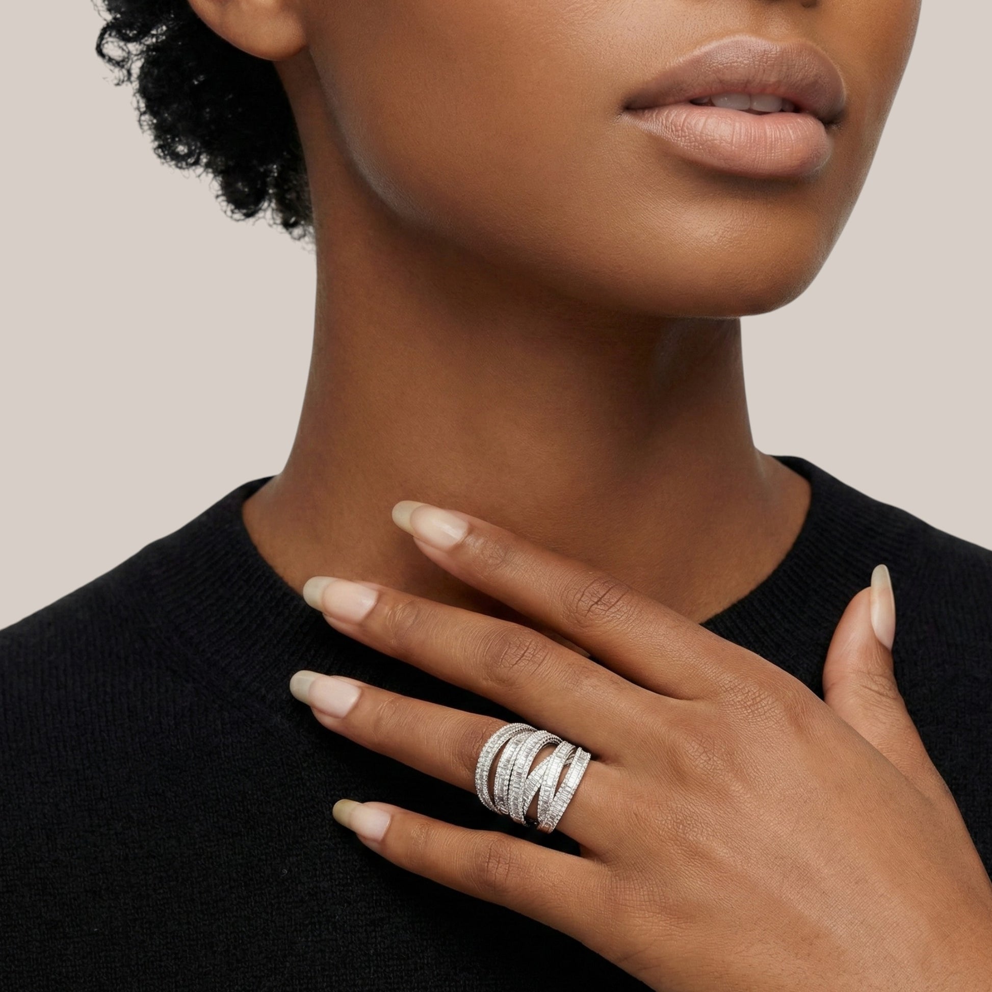 Close-up of a person wearing multiple silver rings on a neutral background