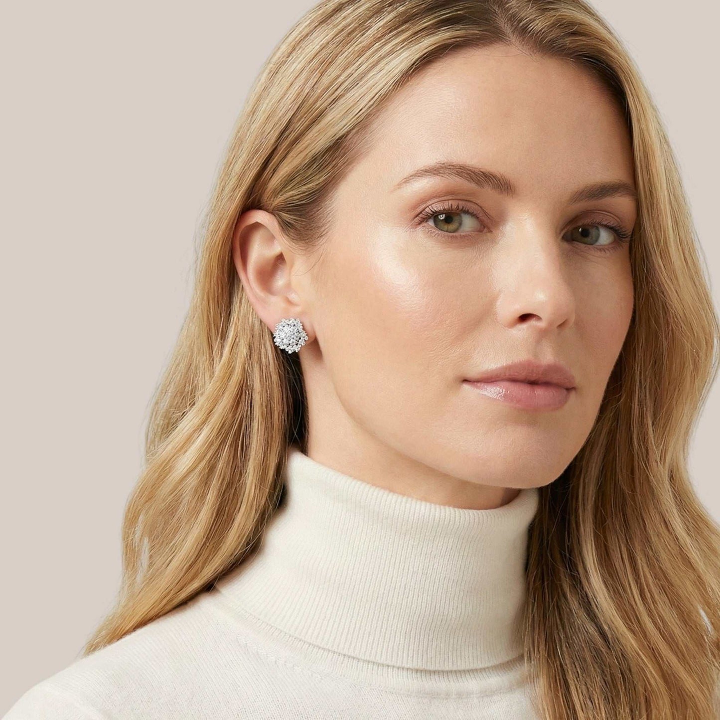 Woman wearing diamond earrings with a neutral background