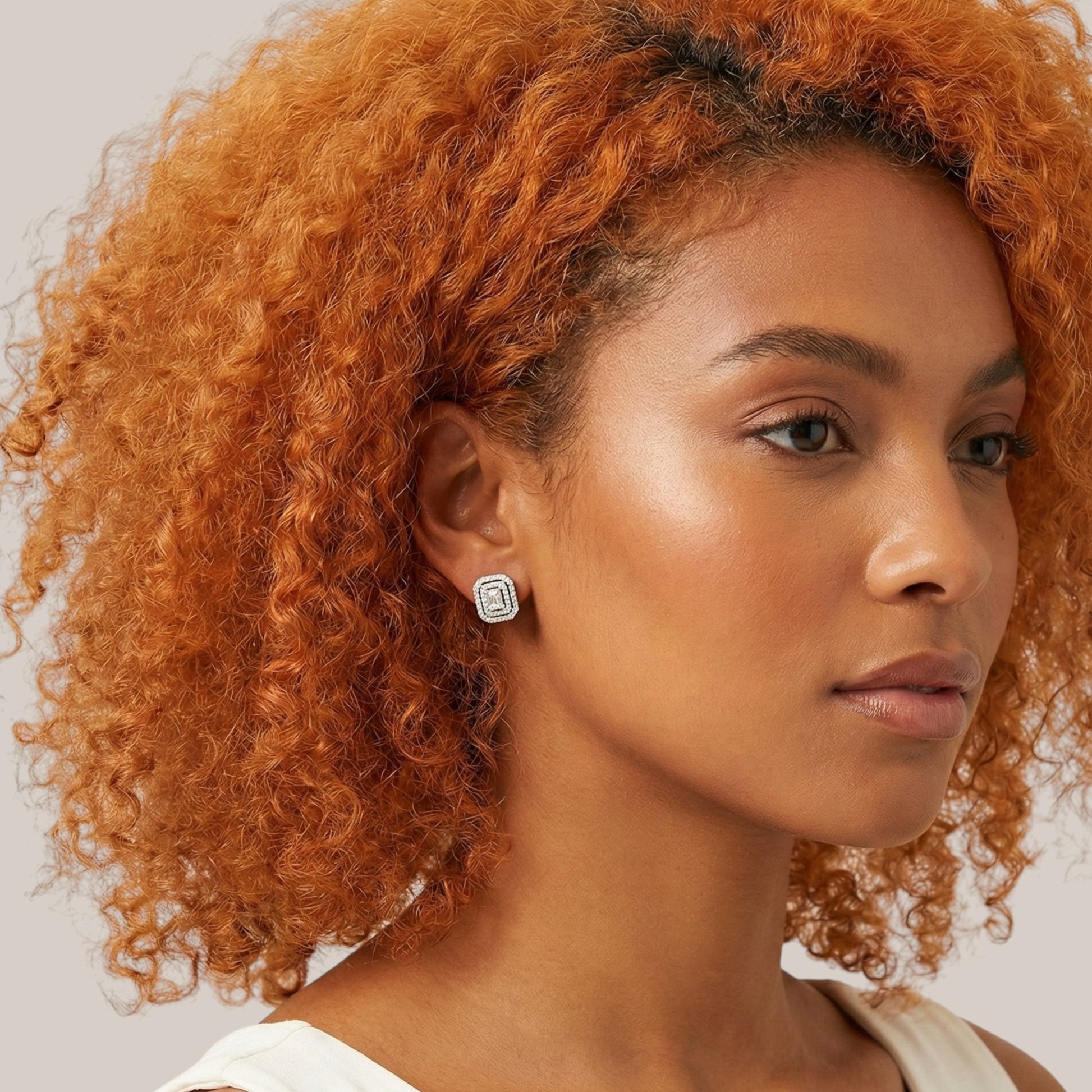 Woman with curly orange hair wearing a white top against a neutral background