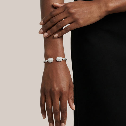 Close-up of a hand wearing a silver bracelet on a plain background