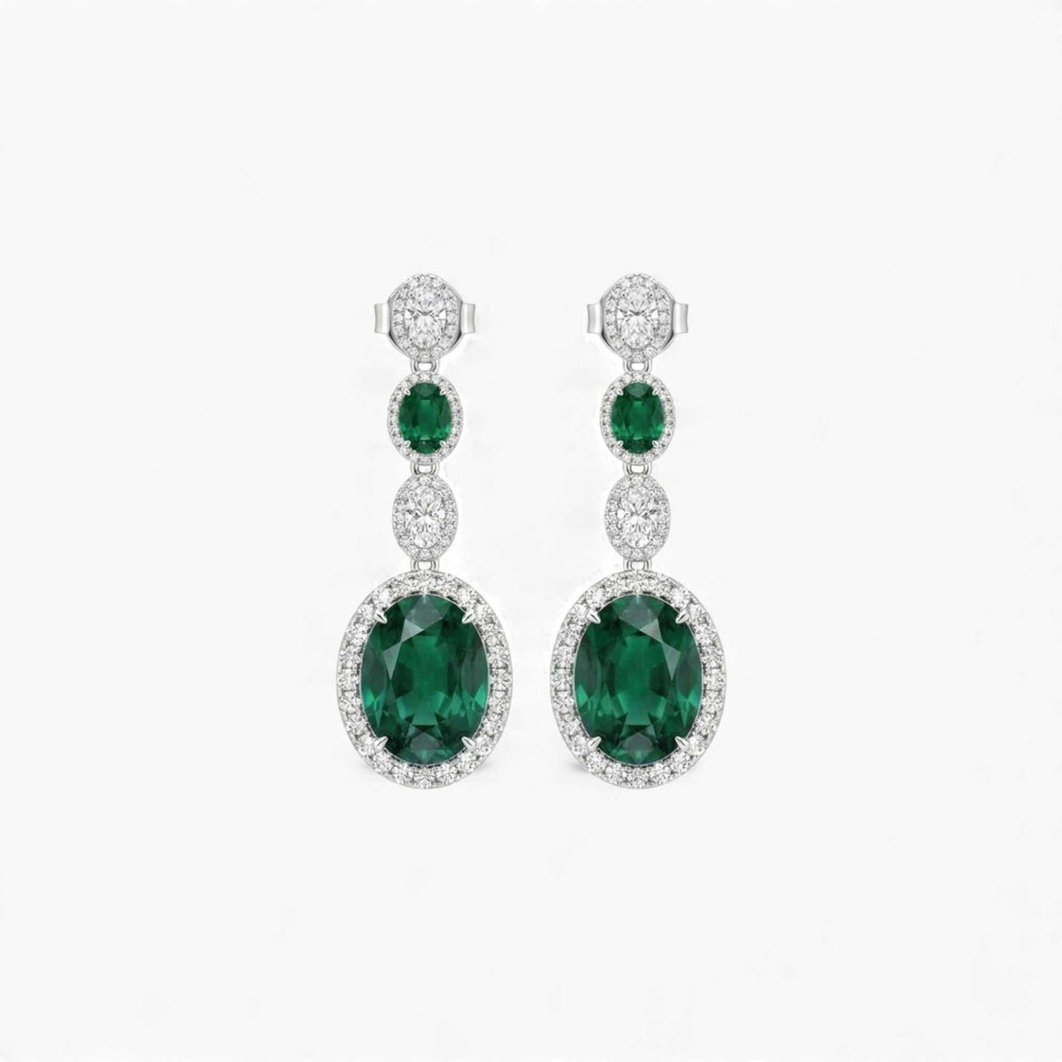 Pair of emerald and diamond earrings on a white background