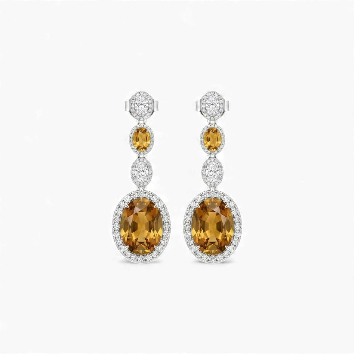 Pair of earrings with yellow gemstones and diamond accents on a white background