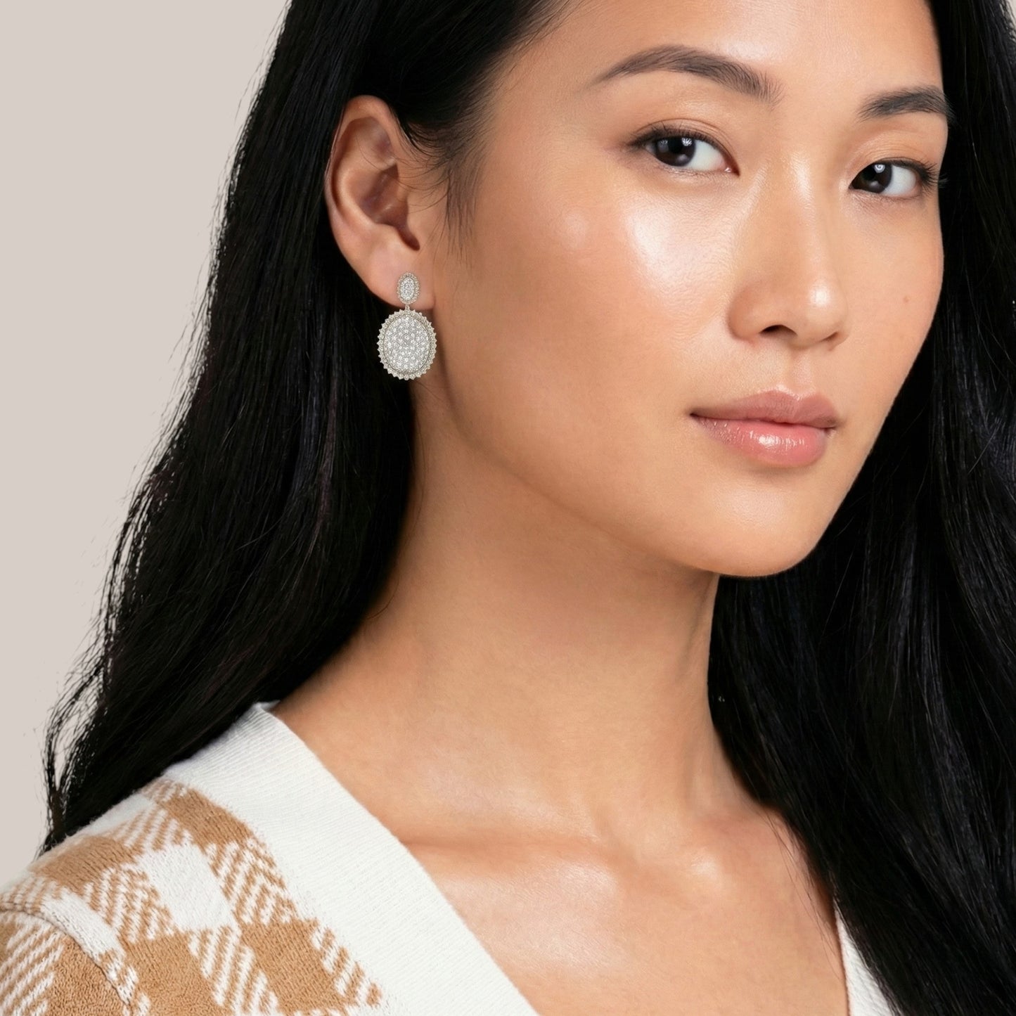 Woman wearing a silver earring with a neutral background