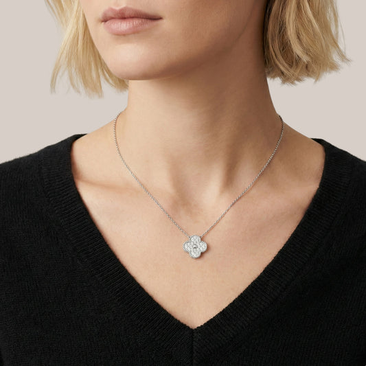 Silver necklace with a floral pendant worn by a person in a black top.