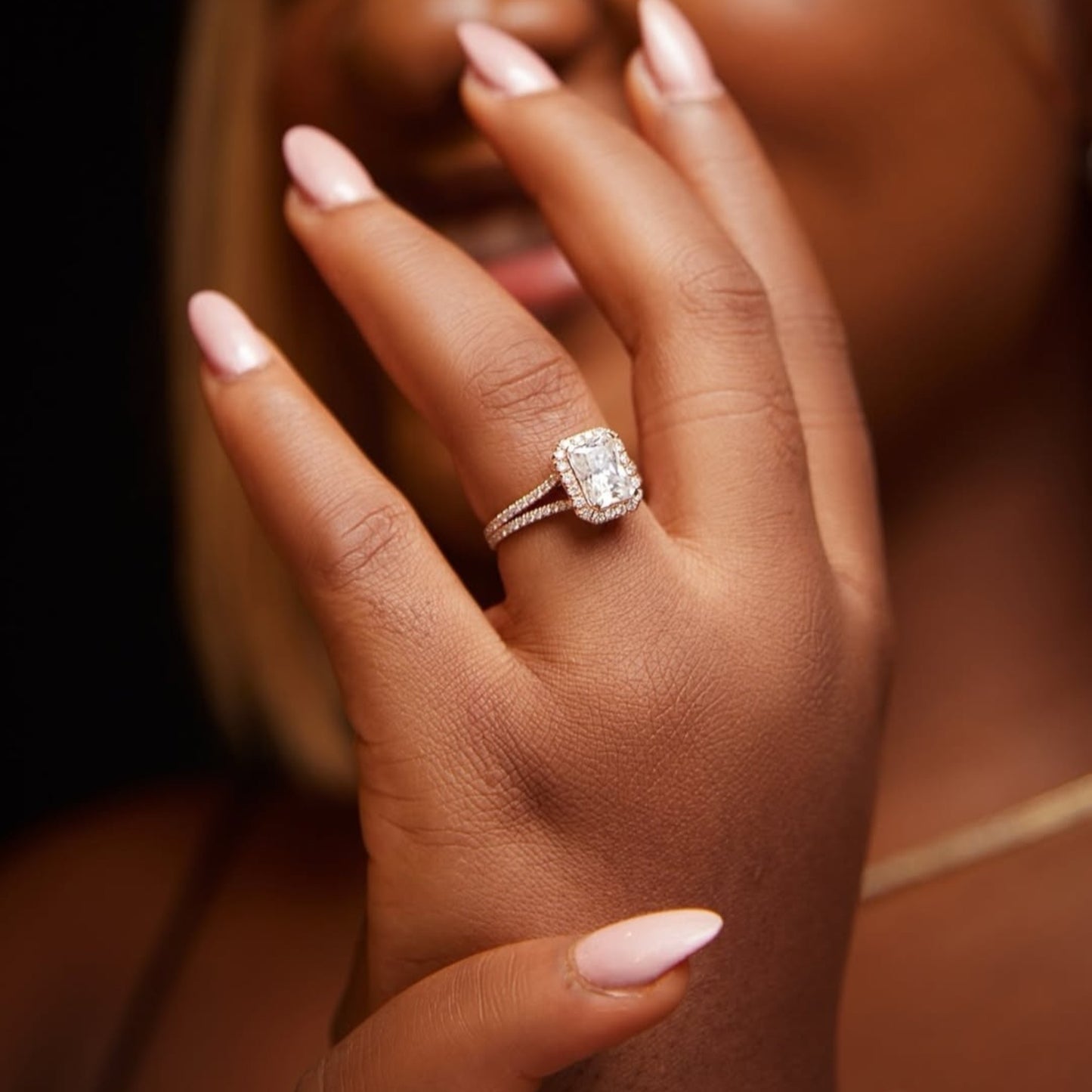 Close-up of a hand wearing a diamond ring with a blurred background