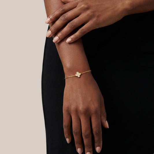 Gold bracelet on a wrist with a plain background