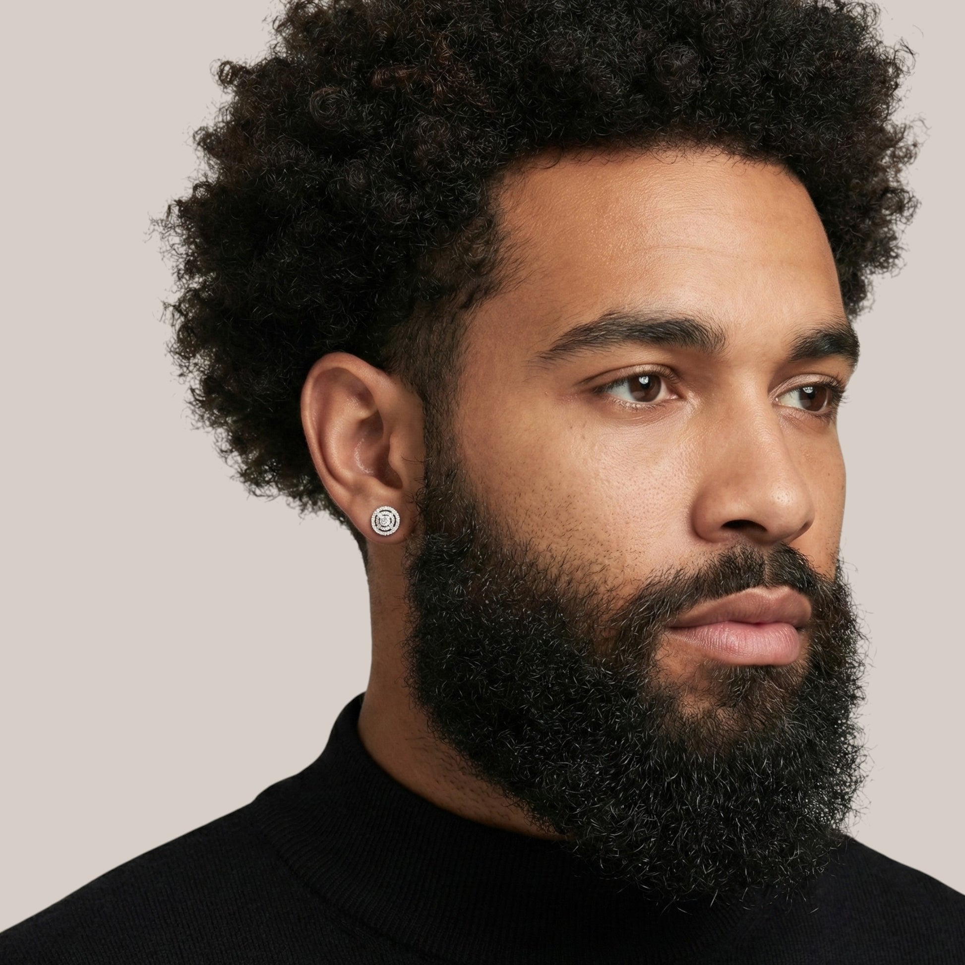Man with a beard wearing a black turtleneck against a plain background