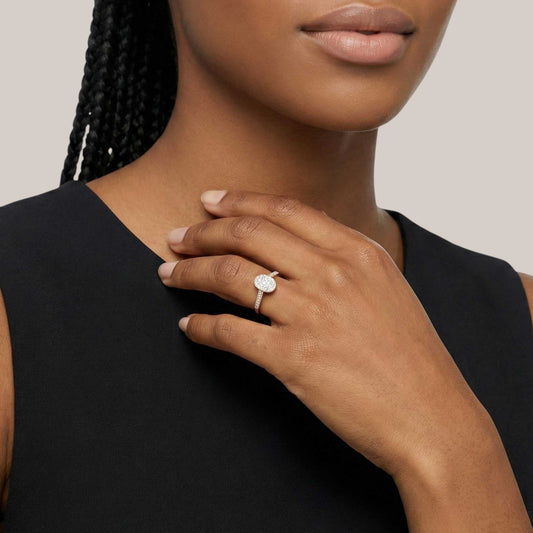 Woman wearing a ring with a diamond on her hand against a neutral background