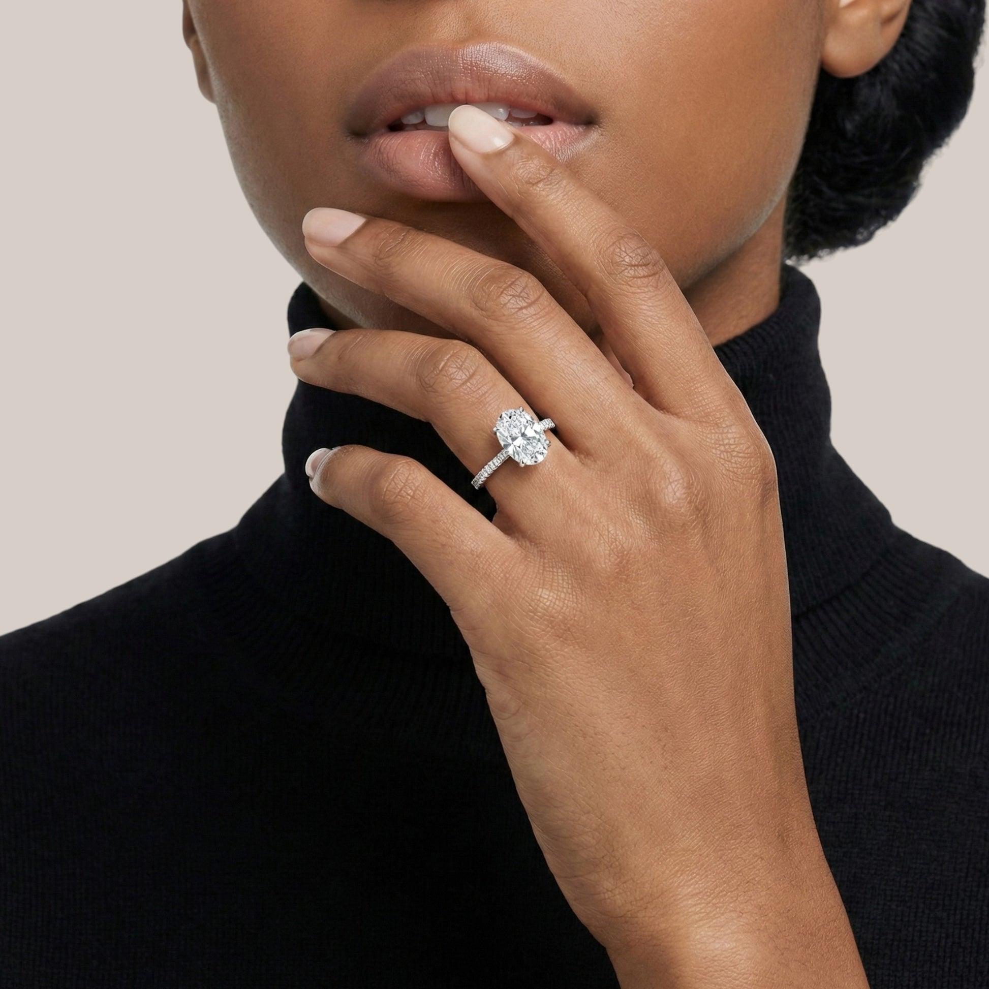Woman wearing a diamond ring on her finger against a neutral background