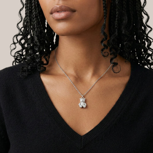 Woman wearing a silver necklace with a bear pendant against a neutral background