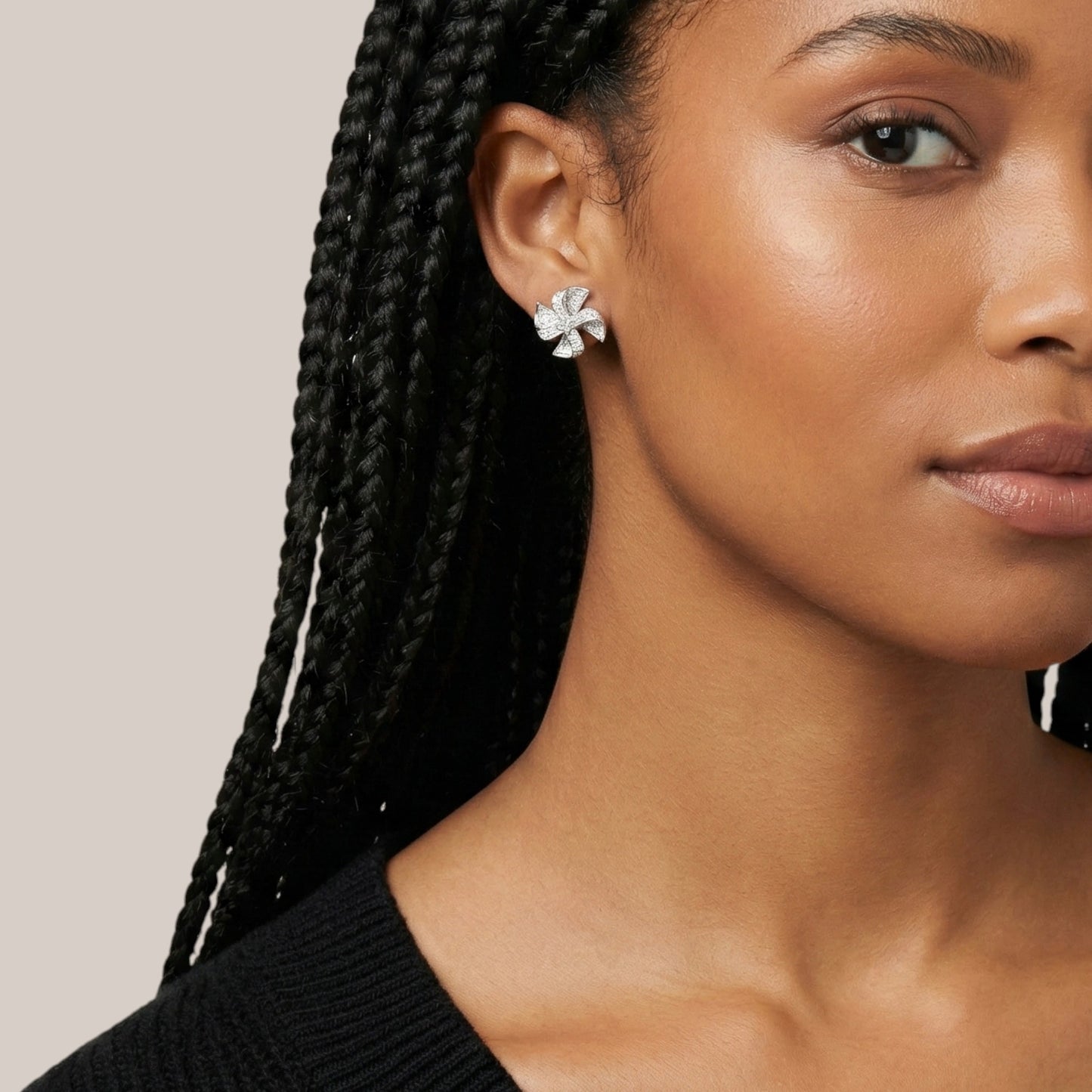 Close-up of a woman wearing a silver earring with a beige background