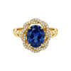 Gold ring with a blue gemstone and diamond accents on a white background
