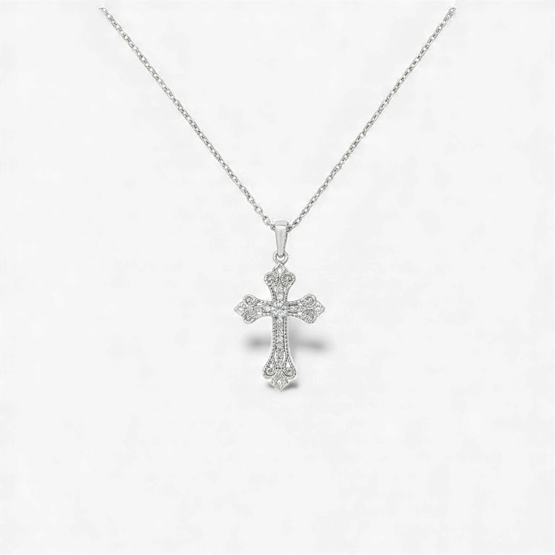 Silver cross pendant necklace on a light gray background
