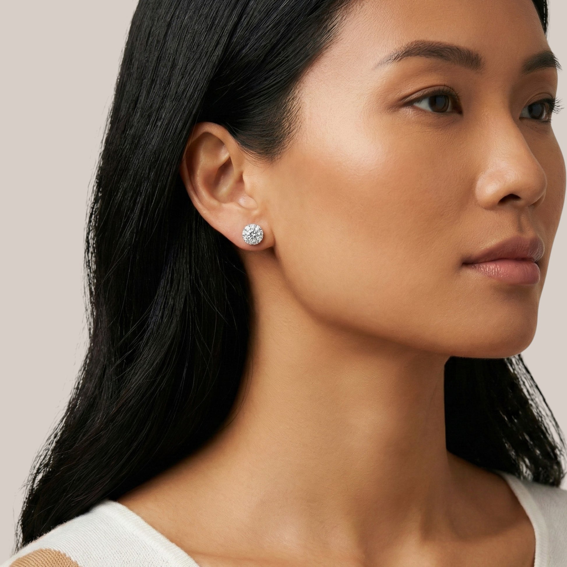 Close-up of a woman wearing diamond earrings with a neutral background