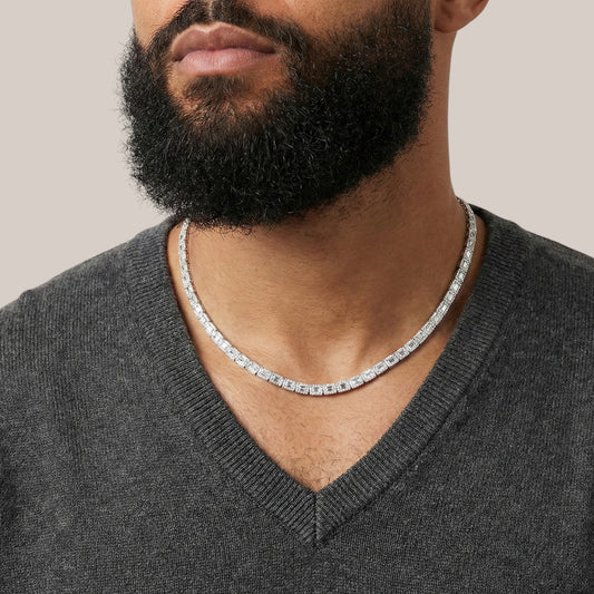 Man wearing a silver chain necklace with a neutral background