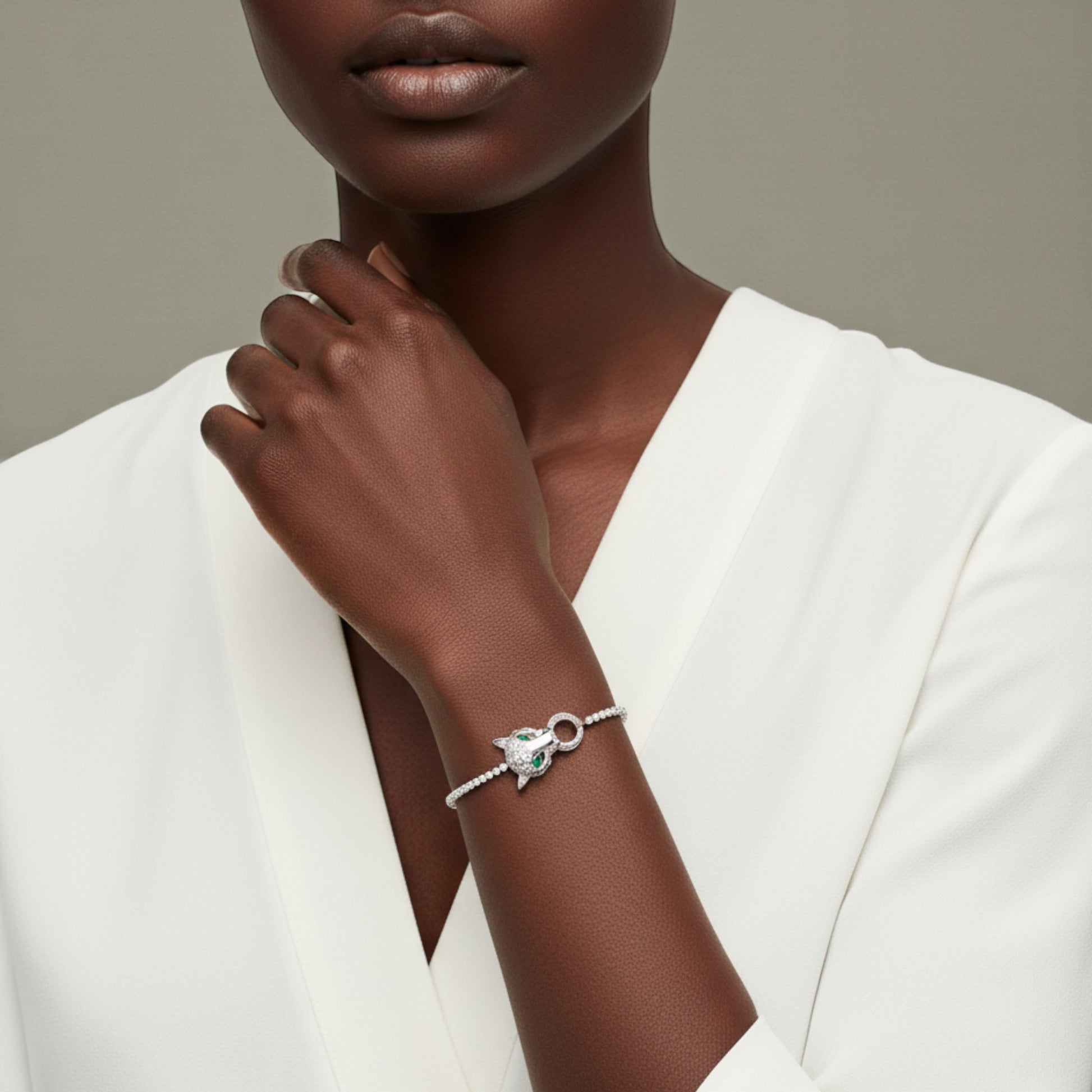 Woman wearing a silver bracelet with a green gemstone on a neutral background