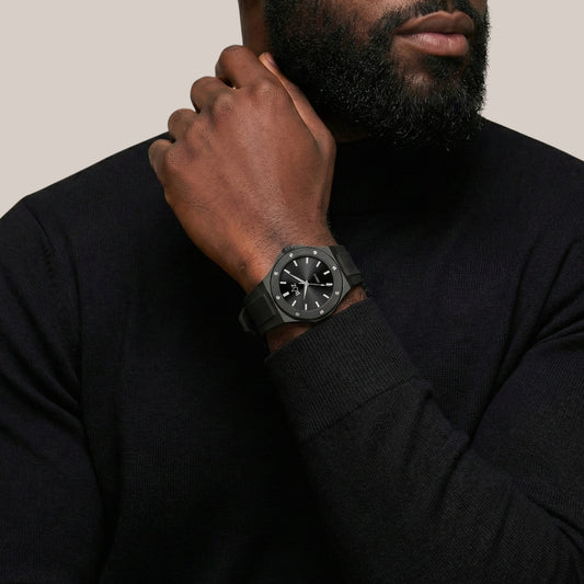 Man wearing a black watch on his wrist with a neutral background
