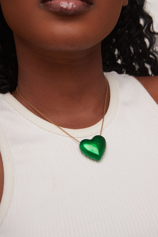 Person wearing a necklace with a green heart pendant