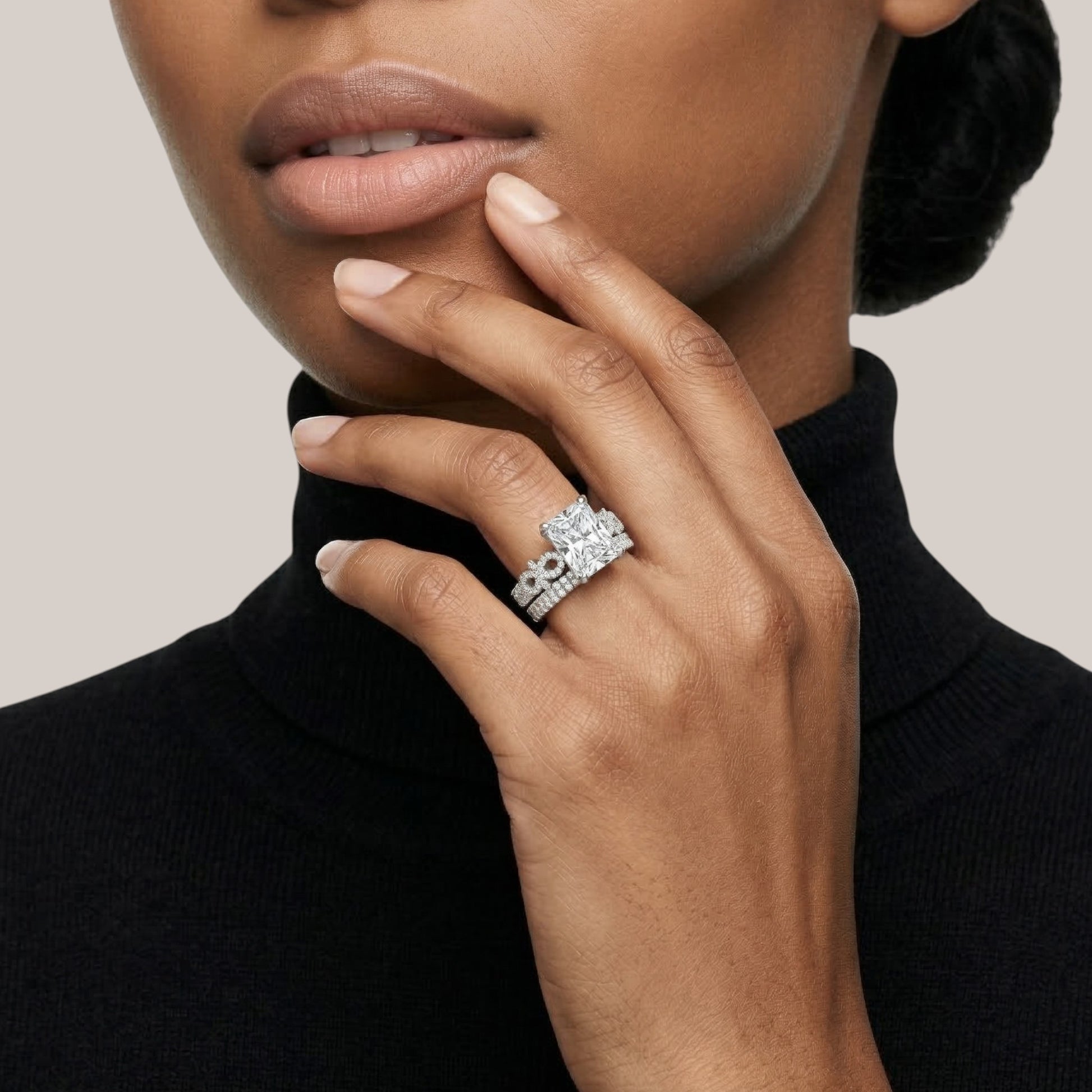 Close-up of a woman's hand wearing a diamond ring on a neutral background