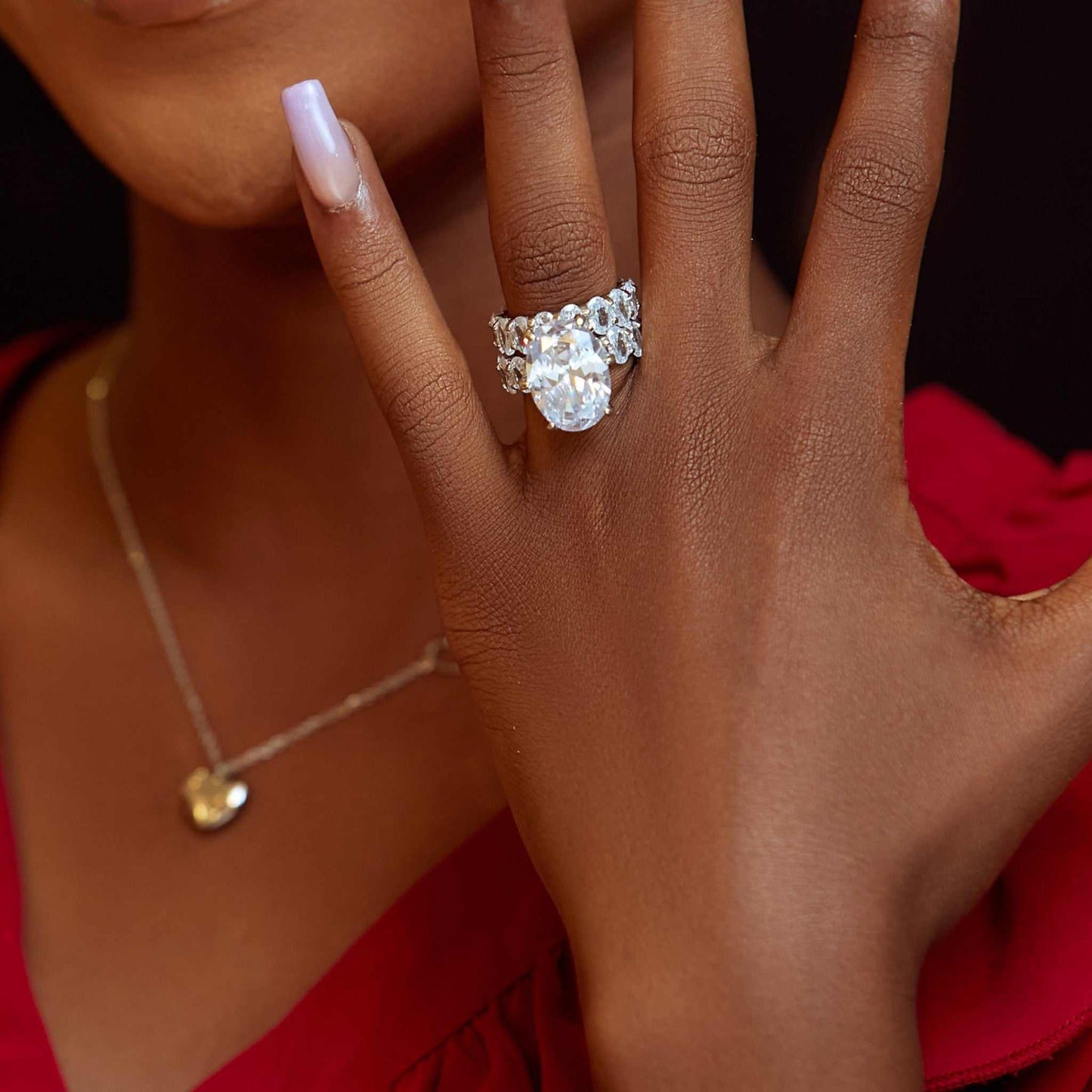 Close-up of hand wearing J Set Oval Cut CZ Bride Set sterling silver ring with large oval cubic zirconia gemstone and matching band