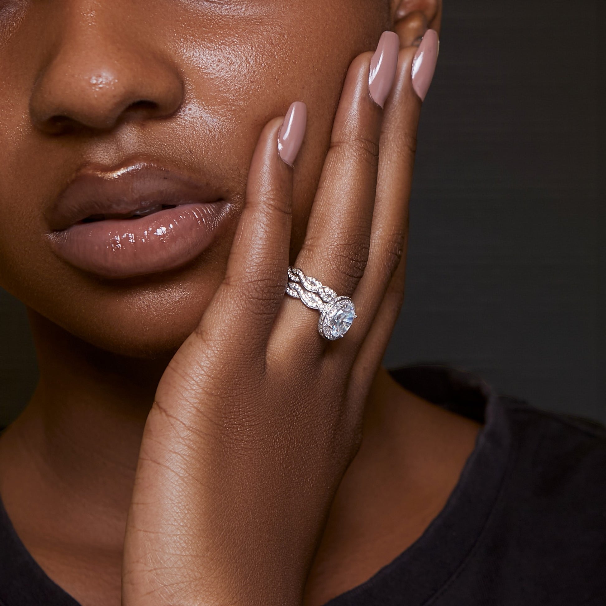 Close-up of a woman's hand wearing a diamond ring with a dark background