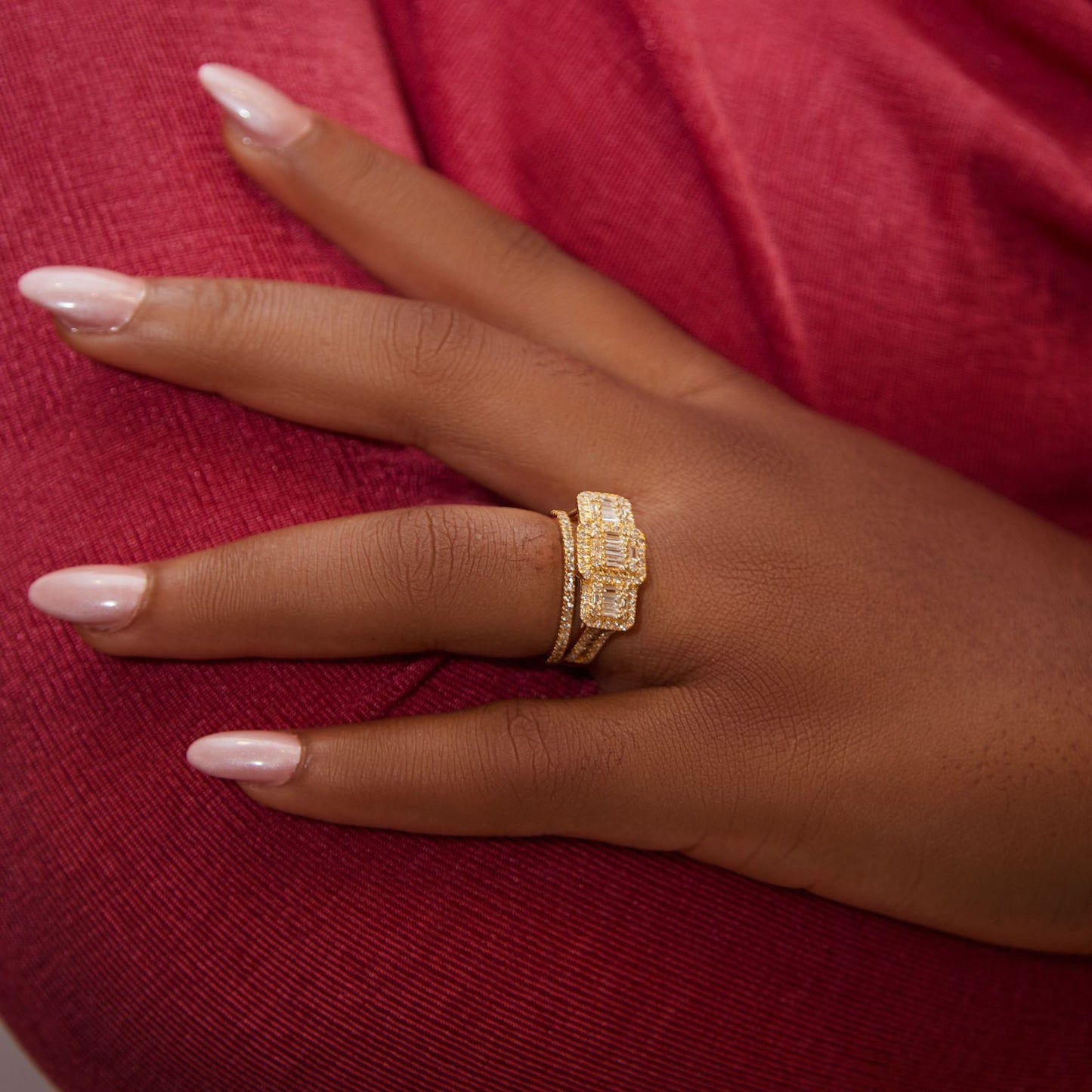 Hand wearing a gold ring on a red fabric background