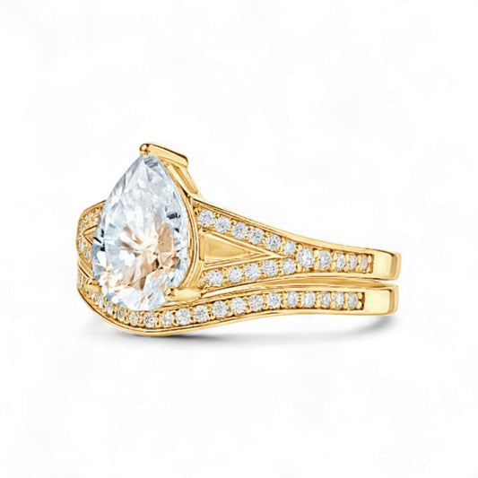 Gold ring with a large pear-shaped diamond and smaller diamonds on the band against a white background