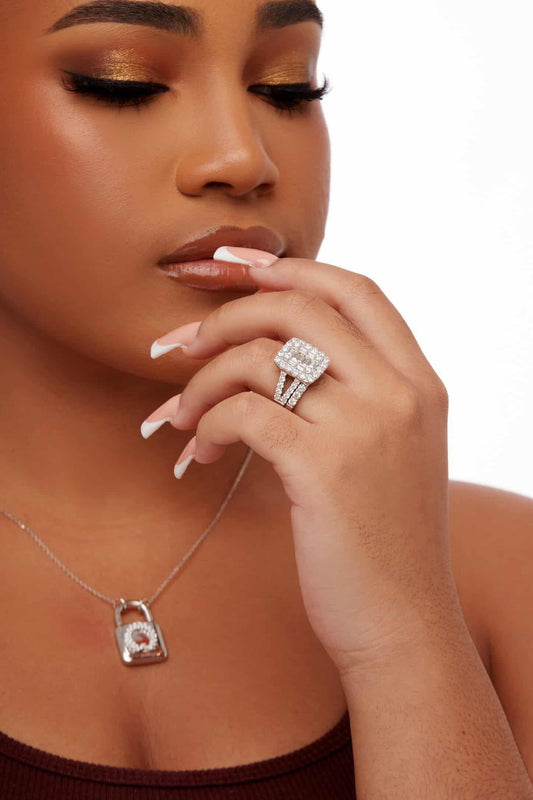 Woman wearing a silver necklace with a lock pendant and a diamond ring on a white background