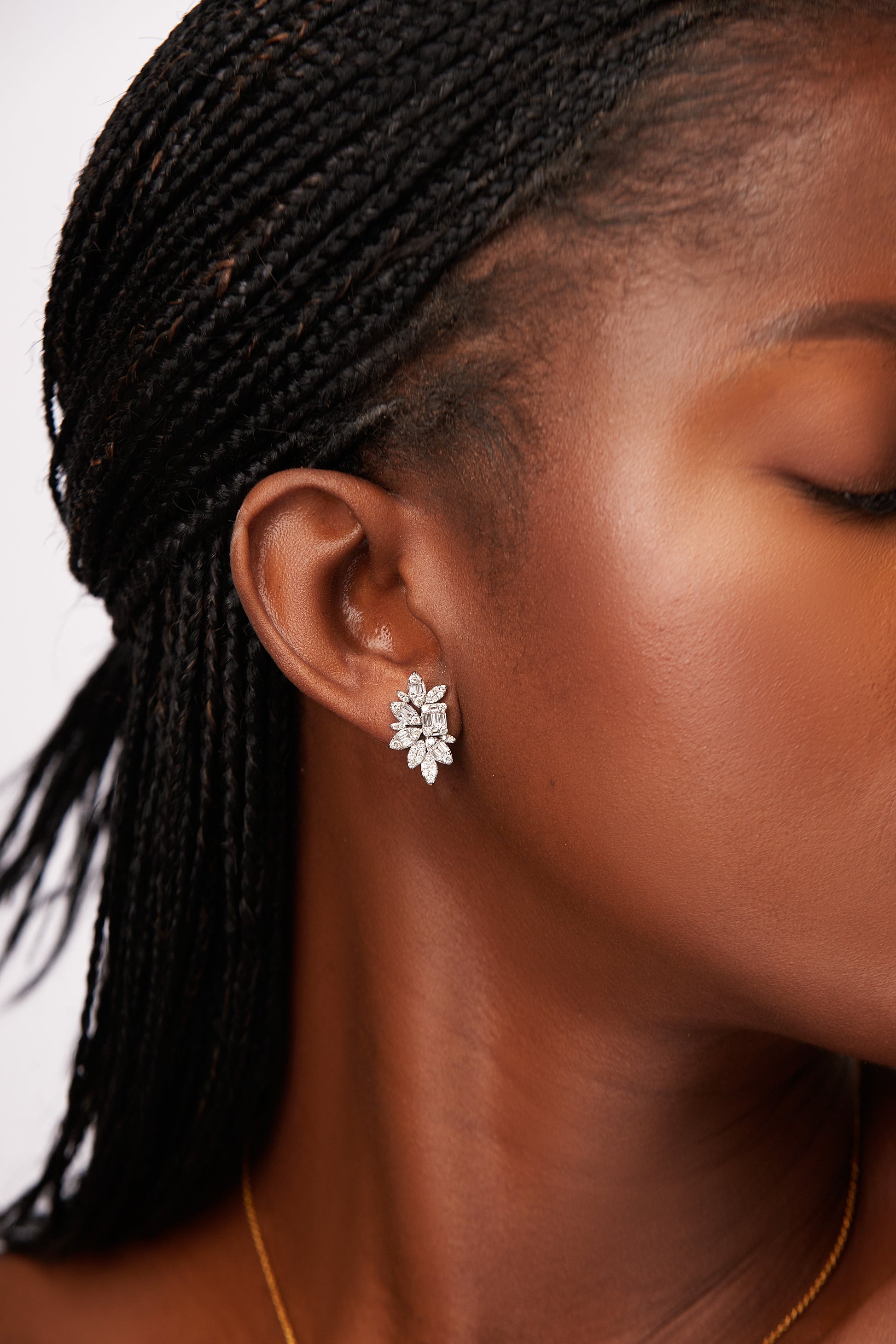 Close-up of a person wearing a silver floral earring with a plain background