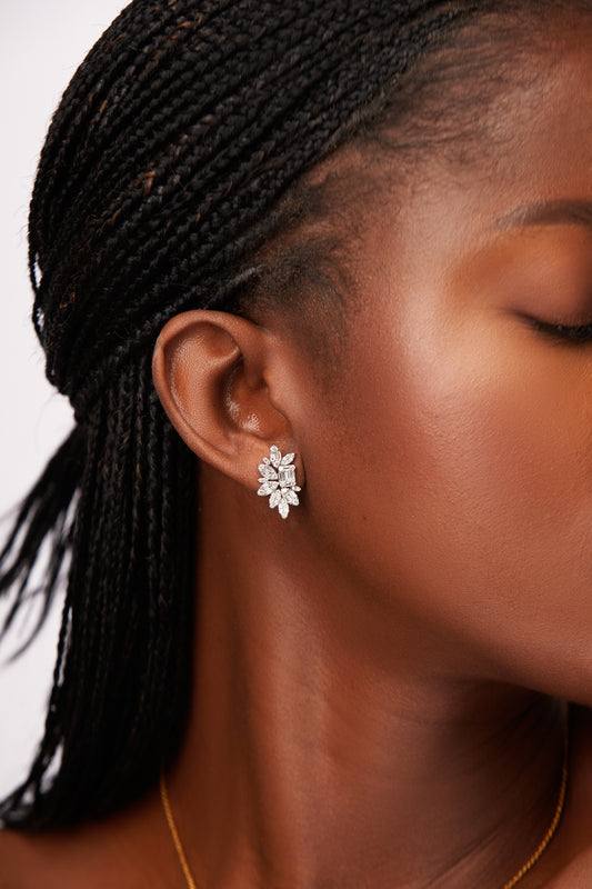 Close-up of a person wearing a silver floral earring with a plain background