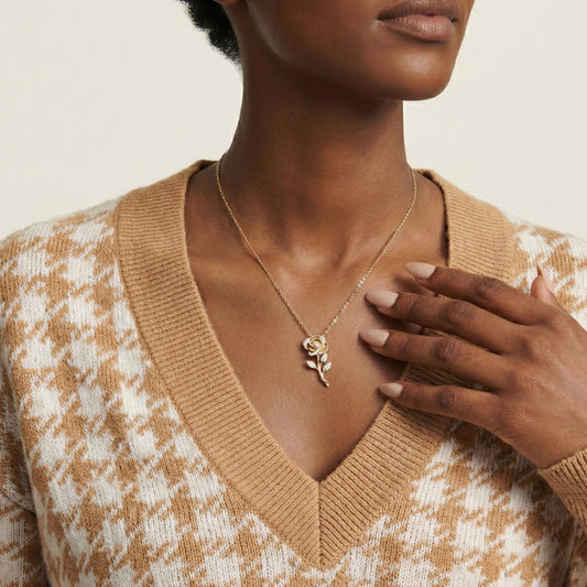 Woman wearing a gold necklace with a rose pendant, wearing a patterned sweater.