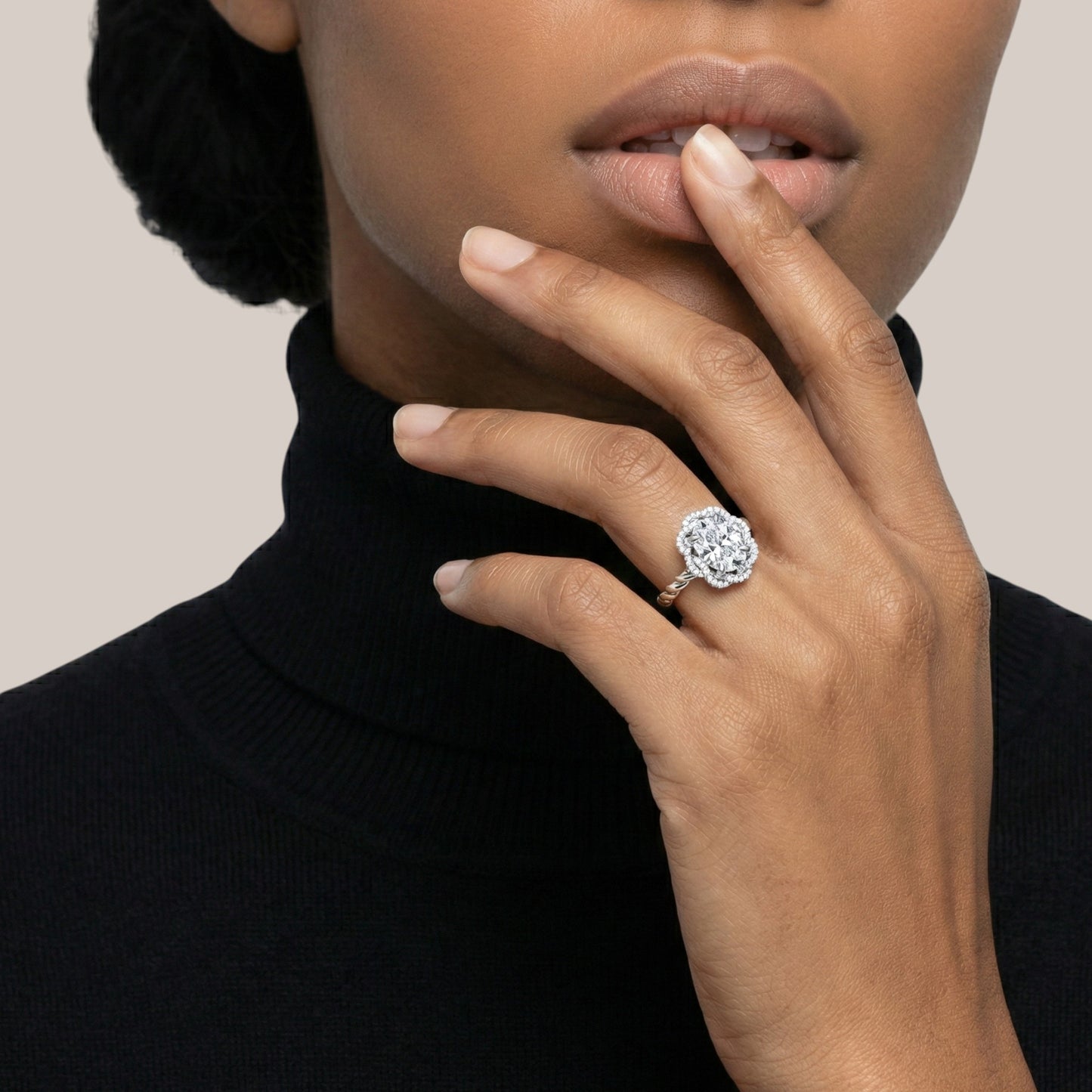 Close-up of a hand wearing a diamond ring with a neutral background