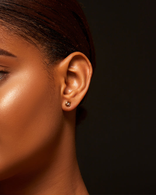 Close-up of a person's ear with an earring against a dark background