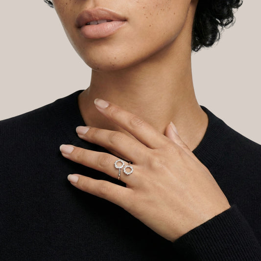 Person wearing a black sweater with a close-up of their hand and ring.