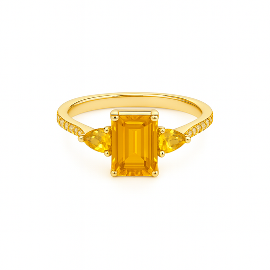 Gold ring with a rectangular yellow gemstone on a white background