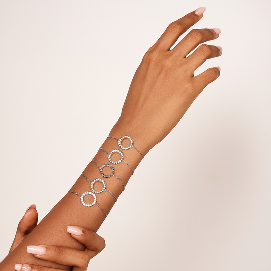 Silver bracelet on a wrist with a plain background