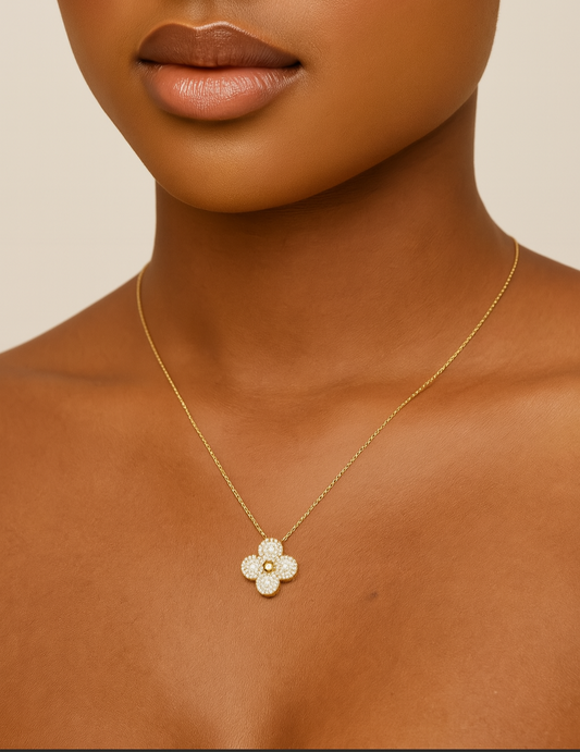 Close-up of a woman wearing a gold necklace with a flower pendant on a beige background