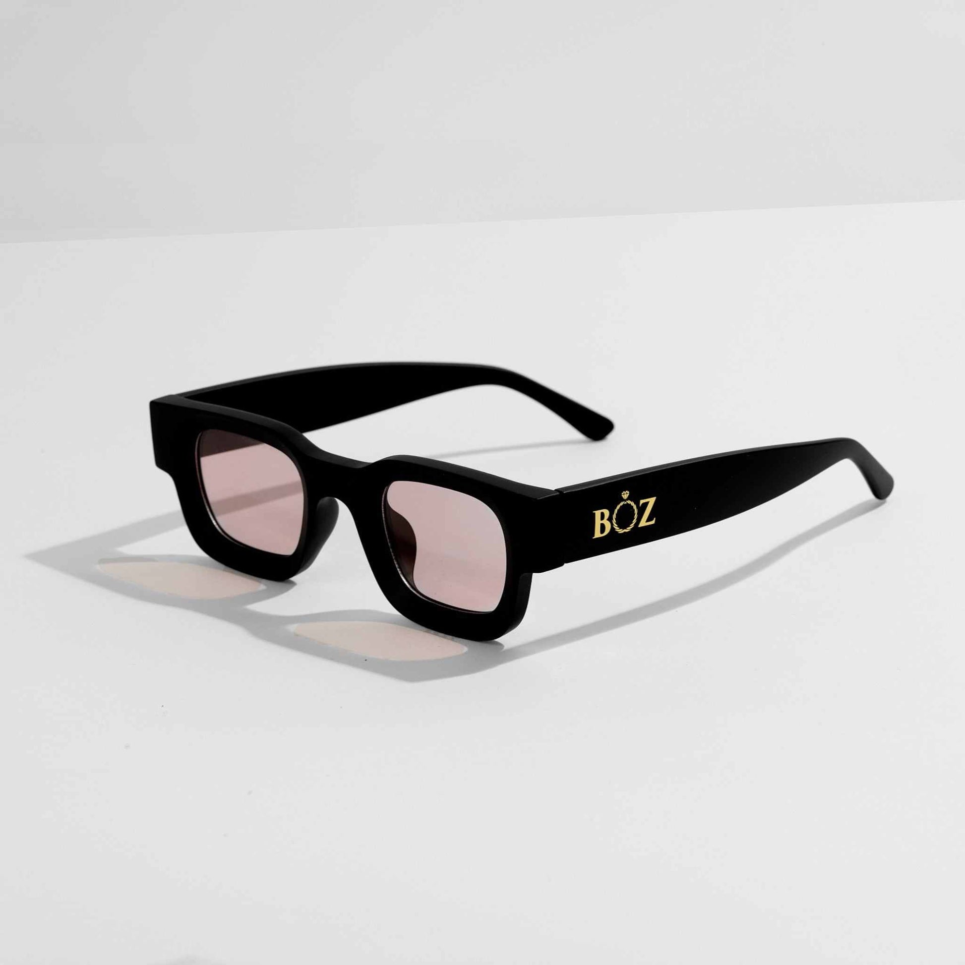 Black sunglasses with pink lenses on a light gray background