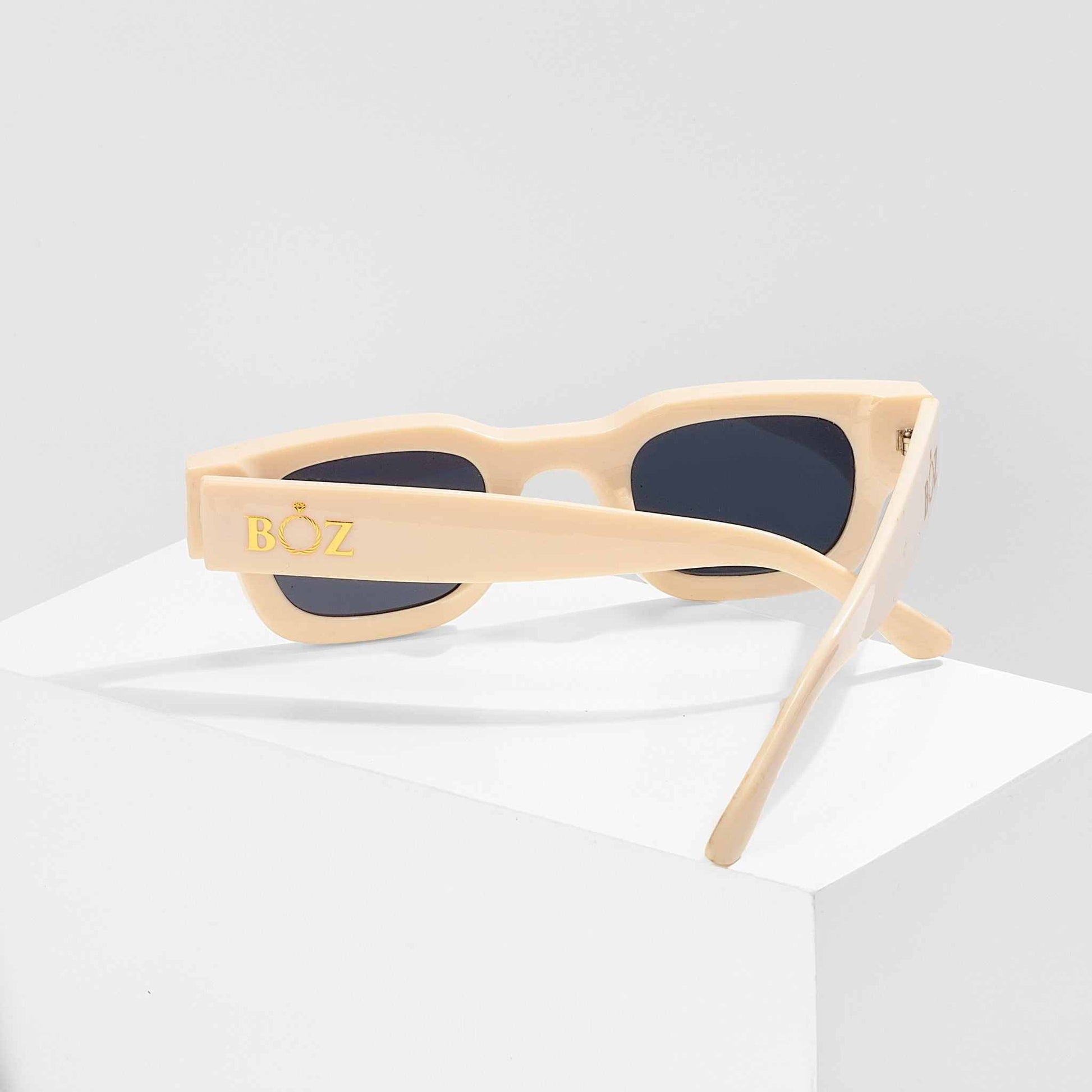 Beige sunglasses with dark lenses on a white background