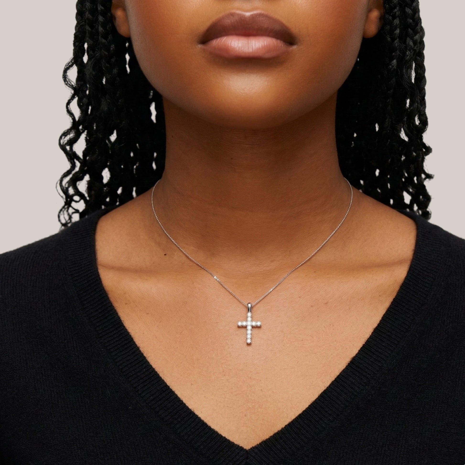 Necklace with a cross pendant worn by a person against a neutral background