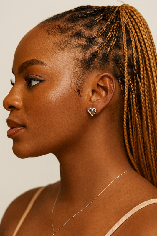 Woman with braided hair wearing a heart-shaped earring and necklace on a neutral background