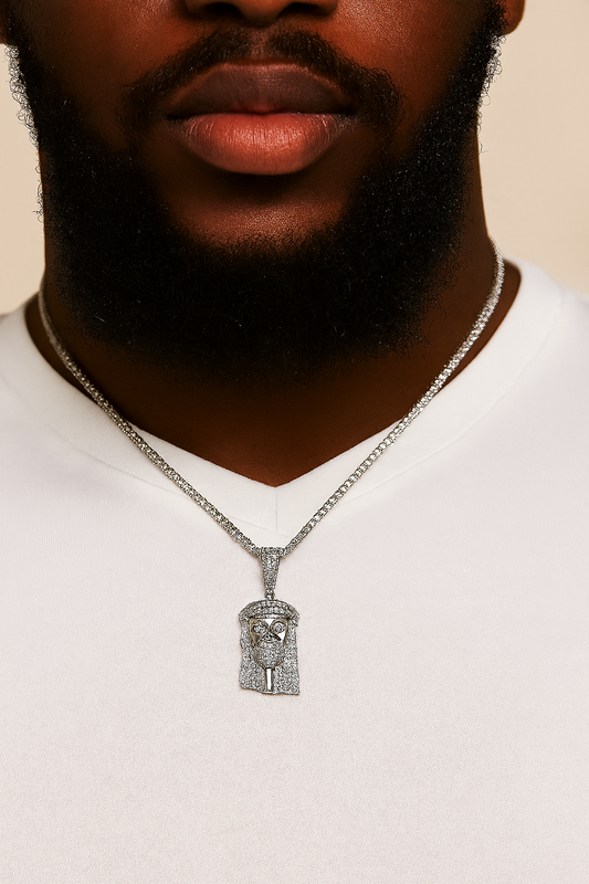 Man wearing a white shirt with a silver necklace featuring a detailed pendant against a beige background