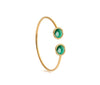 Gold bangle with green gemstones on a white background