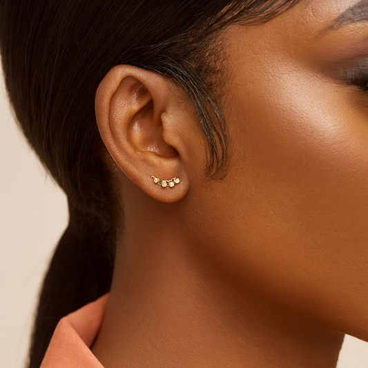 Close-up of an ear wearing a gold earring with a neutral background